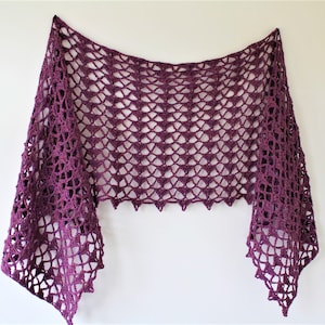 May include: A purple crocheted shawl with a delicate openwork pattern. The shawl is triangular in shape and has a scalloped edge.