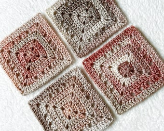 May include: Four crocheted squares in shades of brown, pink, and white. The squares have a granny square pattern with a central circle.