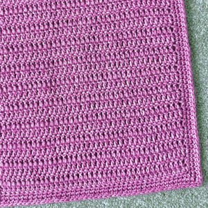 Puede incluir: Primer plano de una tela de crochet rosa con un patrón texturizado.
