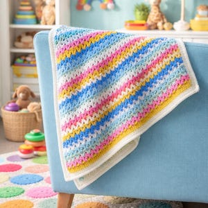 May include: A colorful, handmade crochet blanket draped over a light blue armchair. The blanket features stripes of white, blue, pink, and yellow, with a white border. The room has a rainbow theme, with a rainbow rug and wall decor.