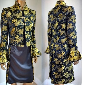 May include: A black and gold brocade jacket with a long tail and ruffled cuffs. The jacket has a mandarin collar and a single button closure.