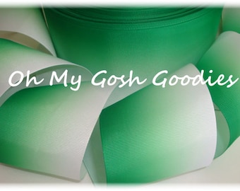 May include: White and green ombre ribbon. The ribbon is a gradient from white to green. The ribbon is folded in half and the green side is facing up. The ribbon is 2.5 inches wide.