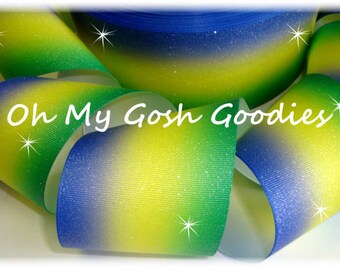 May include: Blue, green, and yellow ombre glitter ribbon. The ribbon has a gradient effect with blue at the top, green in the middle, and yellow at the bottom.