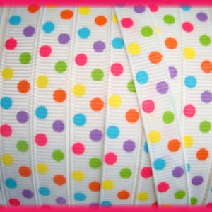 Puede incluir: Cinta blanca con lunares de colores. La cinta tiene un patrón repetitivo de lunares de color rosa brillante, amarillo, naranja, verde, azul y morado.