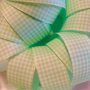 Puede incluir: Primer plano de un paquete de cinta vichy verde y blanca. La cinta está doblada y dispuesta en forma circular.