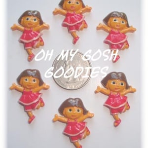 May include: Six small plastic figurines of a cartoon girl wearing a red dress and brown hair. The figurines are about 1 inch tall and are arranged in a circle around a US quarter.