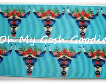 Può includere: Un nastro turchese con un motivo ripetuto di disegni di teschi bianchi, neri e blu con accenti floreali. Il nastro ha il testo "Oh My Gosh Goodies" stampato su di esso.