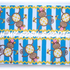 Puede incluir: Cinta de rayas azules y blancas con un patrón repetido de monos marrones que sostienen plátanos. Los monos llevan flores rosas en la cabeza. La cinta tiene un patrón de zigzag amarillo en los bordes.