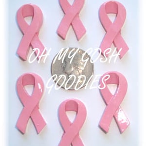 May include: Six pink ribbon charms, each with a glossy finish. The ribbons are tied in a bow shape. The charms are arranged in a circle around a silver coin.