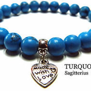 May include: Turquoise blue beaded bracelet with a silver heart charm that says "made with love". The bracelet is labeled "TURQUOISE Sagittarius".