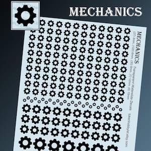Op de afbeelding: Een vel met transparante waterslide-decals met zwarte tandwielvormen in verschillende maten. Het vel bevat 24 decals van 3 mm, 120 decals van 6 mm, 30 decals van 8 mm, 7 decals van 12 mm en 6 decals van 15 mm.