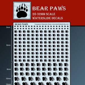 May include: A sheet of waterslide decals with many black bear paw prints. The text "BEAR PAWS" is in red, with "28-32MM SCALE WATERSLIDE DECALS". A small bear paw image is in the upper left corner. Measurements are in millimeters.