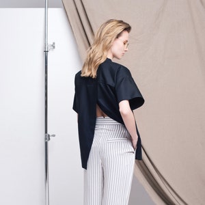 May include: A black short-sleeved shirt with a back cutout and a white and gray striped high-waisted pant.