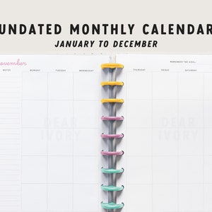 May include: An open, undated monthly calendar with the text "UNDATED MONTHLY CALENDAR JANUARY TO DECEMBER." The calendar is white with a colorful binding and tabs for November and December. The word "November" is in pink.