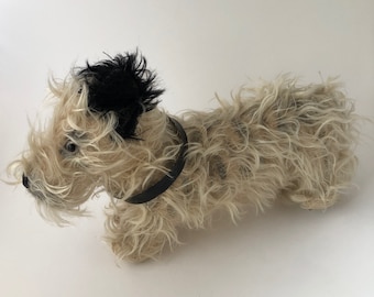 以下が含まれることがあります： 黒い革の首輪をした白黒のぬいぐるみ犬。犬は毛がふさふさしていて、横たわっています。