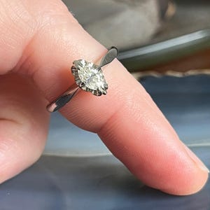Puede incluir: Un anillo de plata con un diamante de forma marquesa engastado en garras.