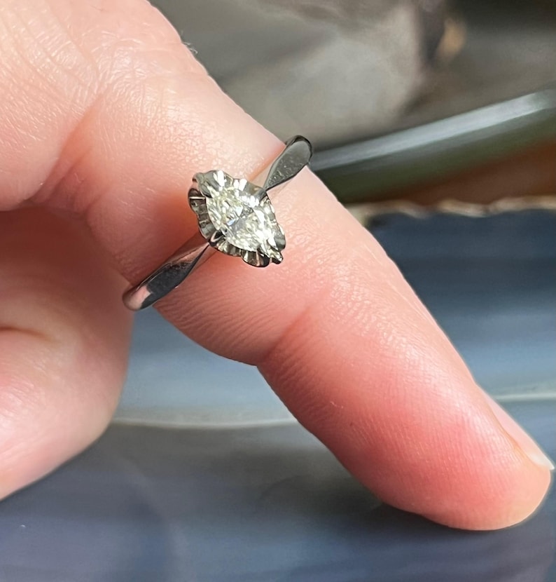 Puede incluir: Un anillo de plata con un diamante de forma marquesa engastado en garras.