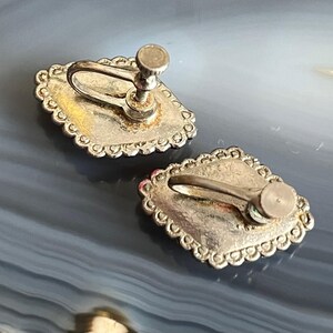 May include: A pair of silver-tone clip-on earrings with a decorative, scalloped edge. The earrings have a silver-tone finish and a clip-on closure.