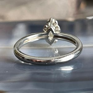 Puede incluir: Un anillo de plata con una piedra preciosa transparente engastada en garras. El anillo es simple y elegante.