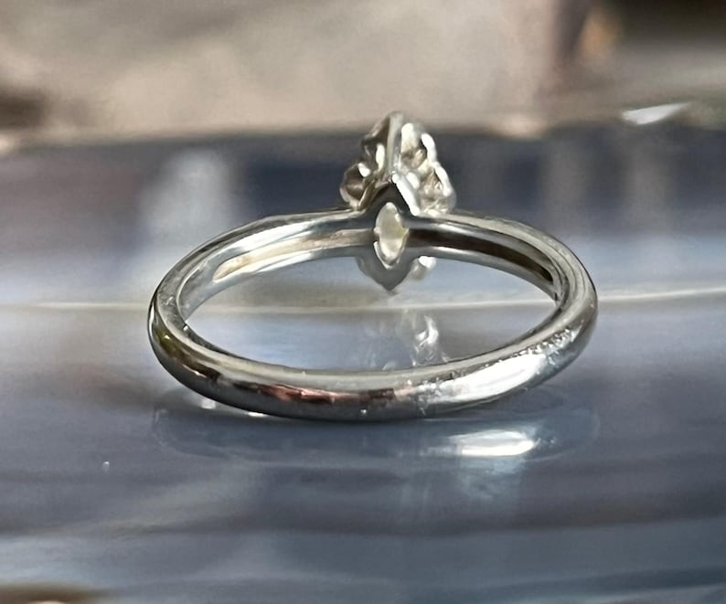 Puede incluir: Un anillo de plata con una piedra preciosa transparente engastada en garras. El anillo es simple y elegante.