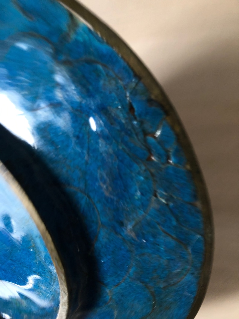 May include: Close-up of a blue ceramic bowl with a crackled glaze. The bowl has a dark blue rim and a light blue interior.