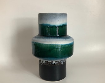 May include: A ceramic vase with a green, white, and black glaze. The vase has a wide base and a narrow neck.