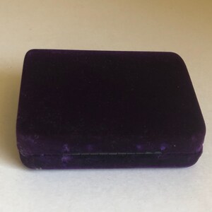 May include: A small, rectangular, purple velvet box with a black lining.