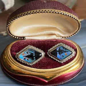 May include: A pair of silver cufflinks with a blue and black butterfly wing design set in a velvet lined box.