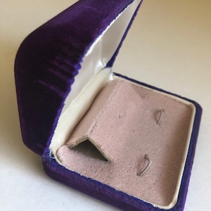May include: A purple velvet jewelry box with a white satin interior and two small slots for earrings.