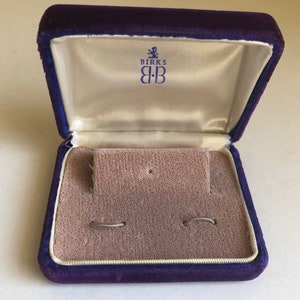May include: A purple velvet jewelry box with a white satin interior. The box has the Birks logo with the text "Birks B:B" on the inside of the lid.