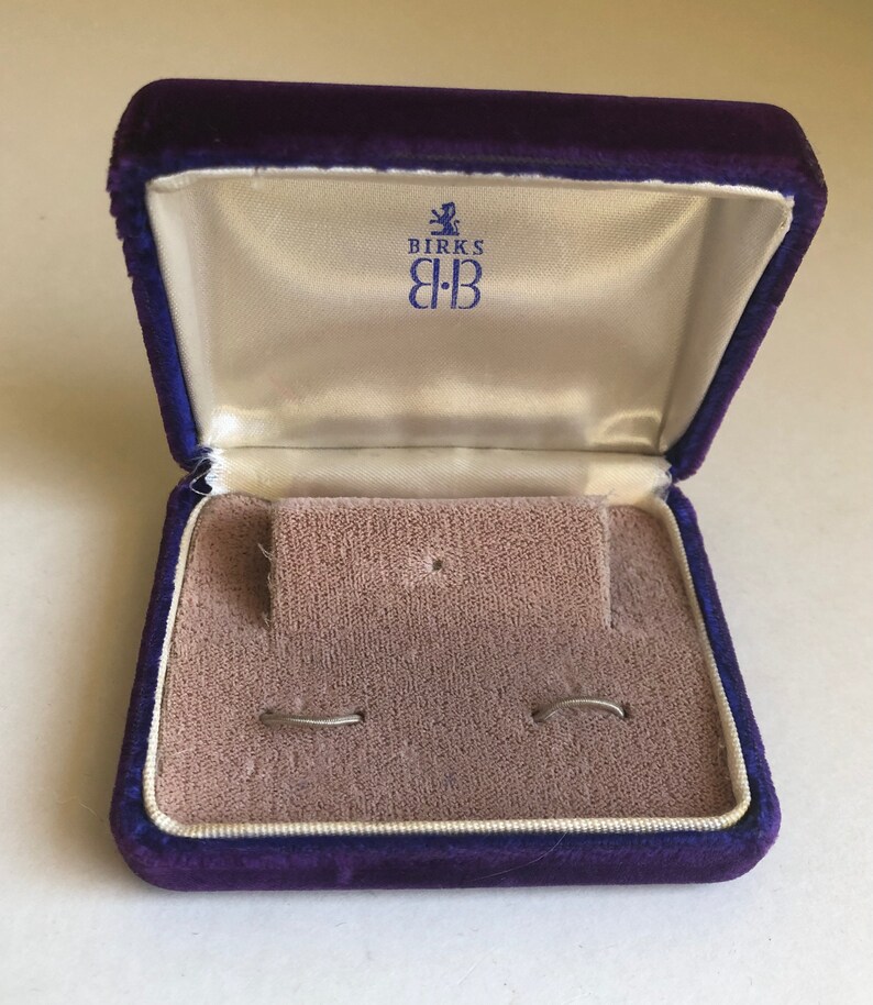 May include: A purple velvet jewelry box with a white satin interior. The box has the Birks logo with the text "Birks B:B" on the inside of the lid.