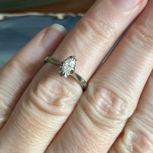 Puede incluir: Un anillo de plata con un diamante de forma marquesa engastado en garras.