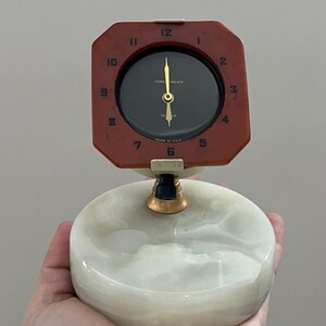 May include: A vintage desk clock with a dark brown octagonal face and a black clock face. The clock has gold hands and a white and green marble base. The clock face reads "PRINC WALKER" and "MADE IN U.S.A."