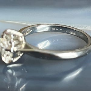 Puede incluir: Un anillo de plata con una banda texturizada y una gran piedra preciosa facetada. El anillo est&aacute; marcado con "14K" en el interior de la banda.