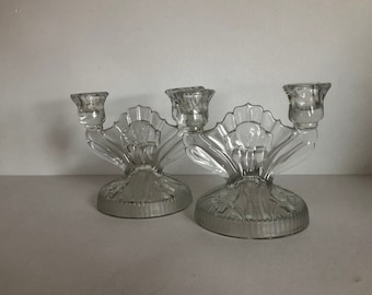 May include: A pair of clear glass candle holders with a floral design. Each holder has three candle cups.