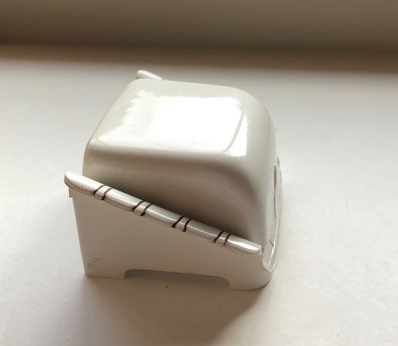 K&ouml;nnte beinhalten: Eine wei&szlig;e Keramik-Butterdose mit Deckel und einem dekorativen Design an der Seite.