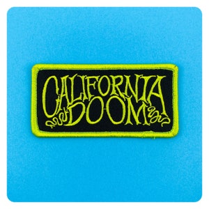 May include: A black and yellow embroidered patch with the text "California Doom" in a stylized font.