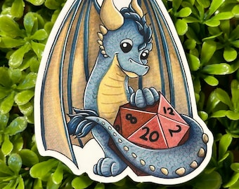 May include: A sticker featuring a cartoon dragon with blue scales, tan wings, and a red twenty-sided die. The dragon is smiling and holding the die. The sticker is on a green leafy background.
