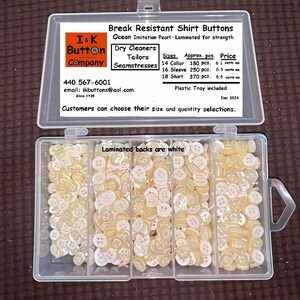May include: A clear plastic container filled with break-resistant shirt buttons. The buttons are ocean imitation pearl, laminated for strength, and have white laminated backs. The container is divided into sections, each filled with a different quantity of buttons.