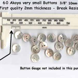 May include: Sixty white mother-of-pearl buttons, each measuring 3/8 inch (10 mm) in diameter. The buttons are arranged on a white surface with a ruler for scale. The text "60 Akoya very small Buttons 3/8" 10mm First quality 2mm thickness - Break Resistant" is visible above the buttons.