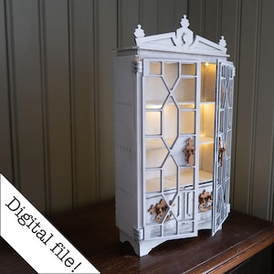 以下が含まれることがあります： ガラスのドアと棚が付いた白い木製のキャビネット。キャビネットは装飾的な天板があり、ライトで照らされています。