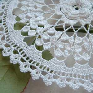 Puede incluir: Doily de ganchillo blanco con un delicado dise&ntilde;o floral. El doily est&aacute; hecho con un hilo fino y tiene un aspecto delicado y de encaje.