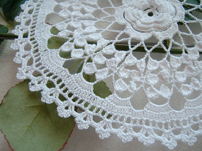Puede incluir: Doily de ganchillo blanco con un delicado dise&ntilde;o floral. El doily est&aacute; hecho con un hilo fino y tiene un aspecto delicado y de encaje.