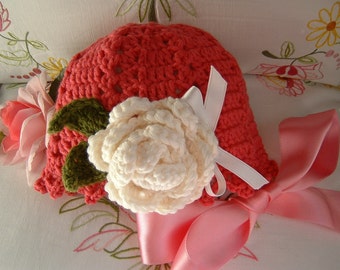 Crochet baby hat in dark pink wool with a rose applied. Children's fashion Idea winter. Romantic and feminine style.