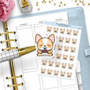 Puede incluir: Una agenda con un bolígrafo dorado, una hoja de pegatinas de corgi y una pegatina grande de corgi. Las pegatinas de corgi tienen un corgi sonriente comiendo de un cuenco. La agenda está abierta en una página en blanco con los días de la semana.