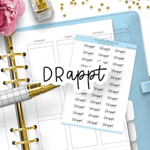 May include: A sheet of white planner stickers featuring the repeated black text "DRappt" in a handwritten script font, positioned on a light blue planner with gold rings, a white and black grid pen, and a pink flower accent.