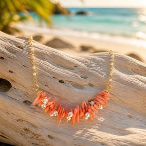 May include: A necklace featuring a gold chain interspersed with small white pearls, leading to a central cluster of irregular, branch-like peach-colored coral pieces accented with additional small white pearls and gold-toned metal beads.