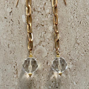 May include: A pair of gold chain earrings with clear faceted crystal ball drop charms.