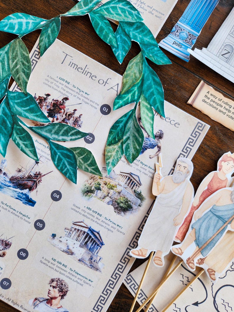 May include: A tabletop display featuring a timeline of ancient Greece, illustrated with images and text. Includes paper cutouts of figures, a decorative green leaf garland, and architectural elements. The text includes the words "Timeline of A" and "Greece".