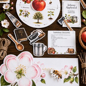 May include: A collection of educational paper cutouts featuring a circular apple life cycle chart, a Johnny Appleseed vocabulary field guide, a saddlebag challenge card, a bee, apple blossoms, a hammer, a saw, an axe, a Bible, and a tin cup.